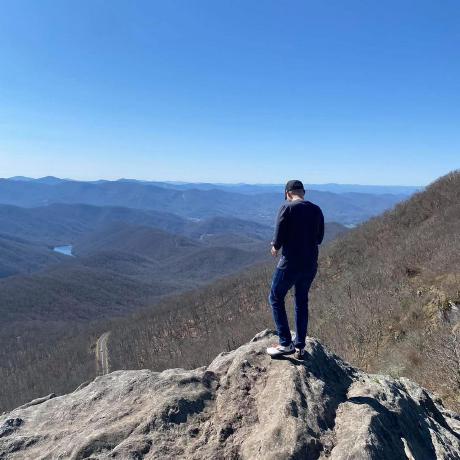 photo of the developer, faced away, standing on a mountain overlooking a valley